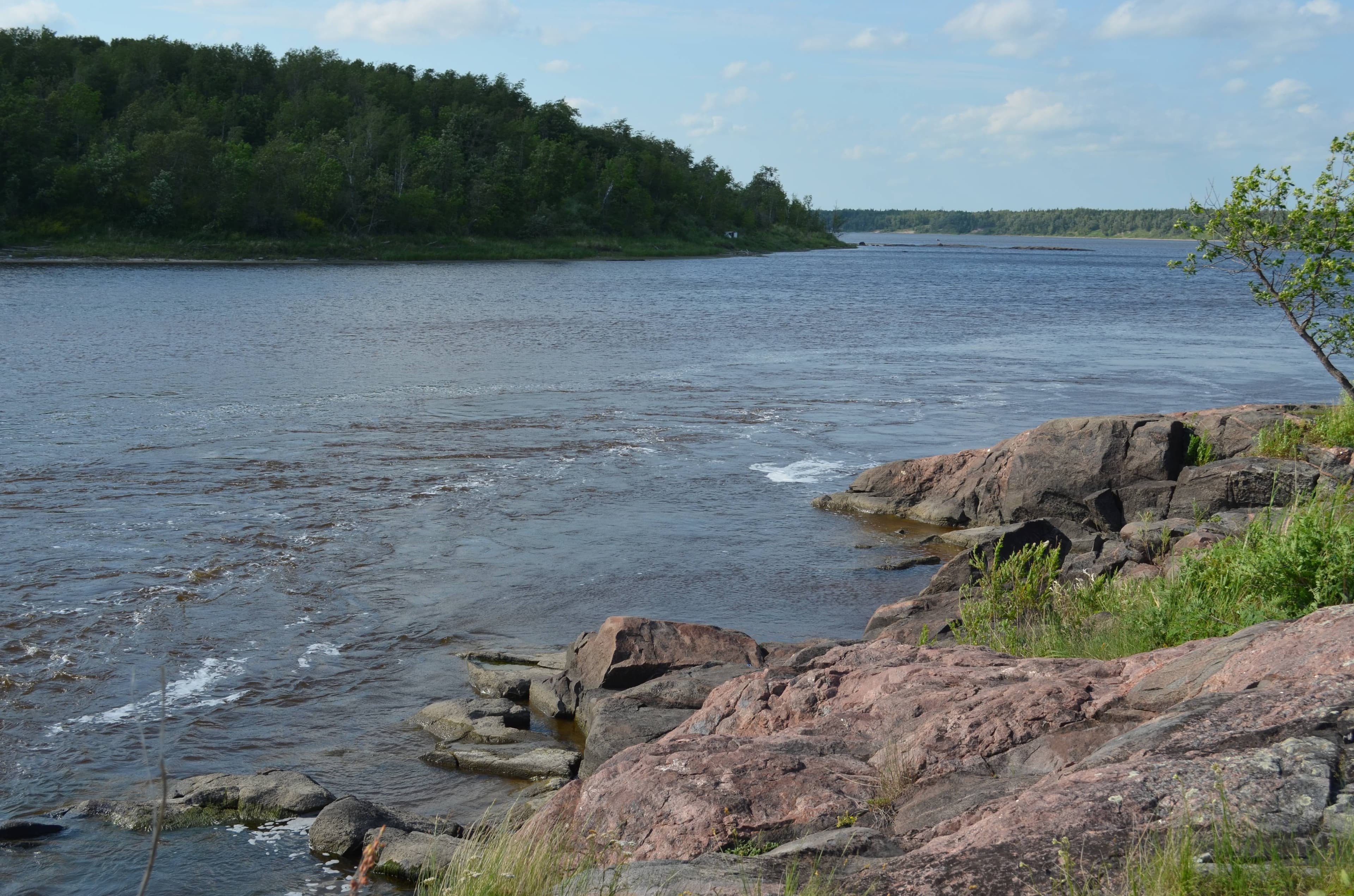 A rocky granite shore and boreal forest along a river in Manitoba's Whiteshell