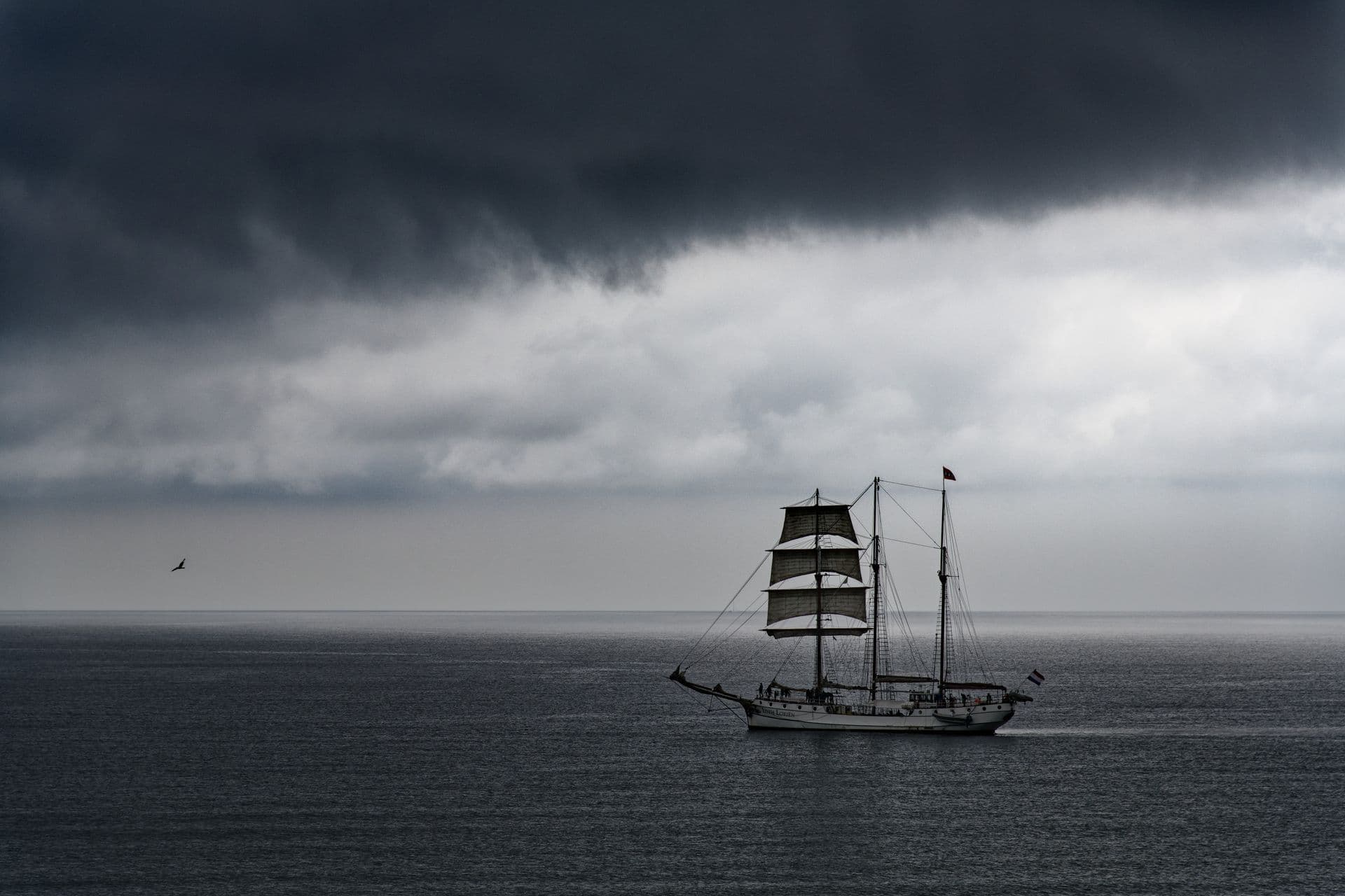 A lone vessel on dark, heaving seas under a bruised sky, the kind of water that earned Cape Hatteras the name Graveyard of the Atlantic