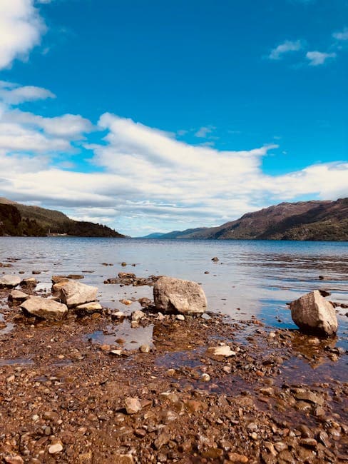 Tranquil Loch Ness shoreline with clear sky and distant hills in the Scottish Highlands