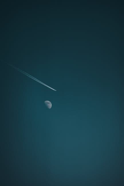 Jet contrail crossing in front of the moon against a dark night sky