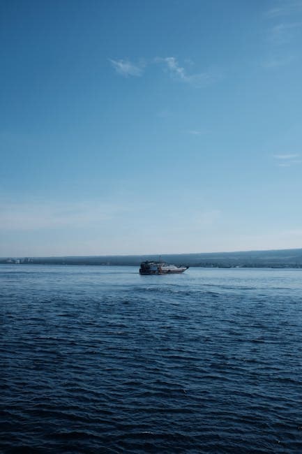 A lone ship on a vast calm ocean under a clear blue sky