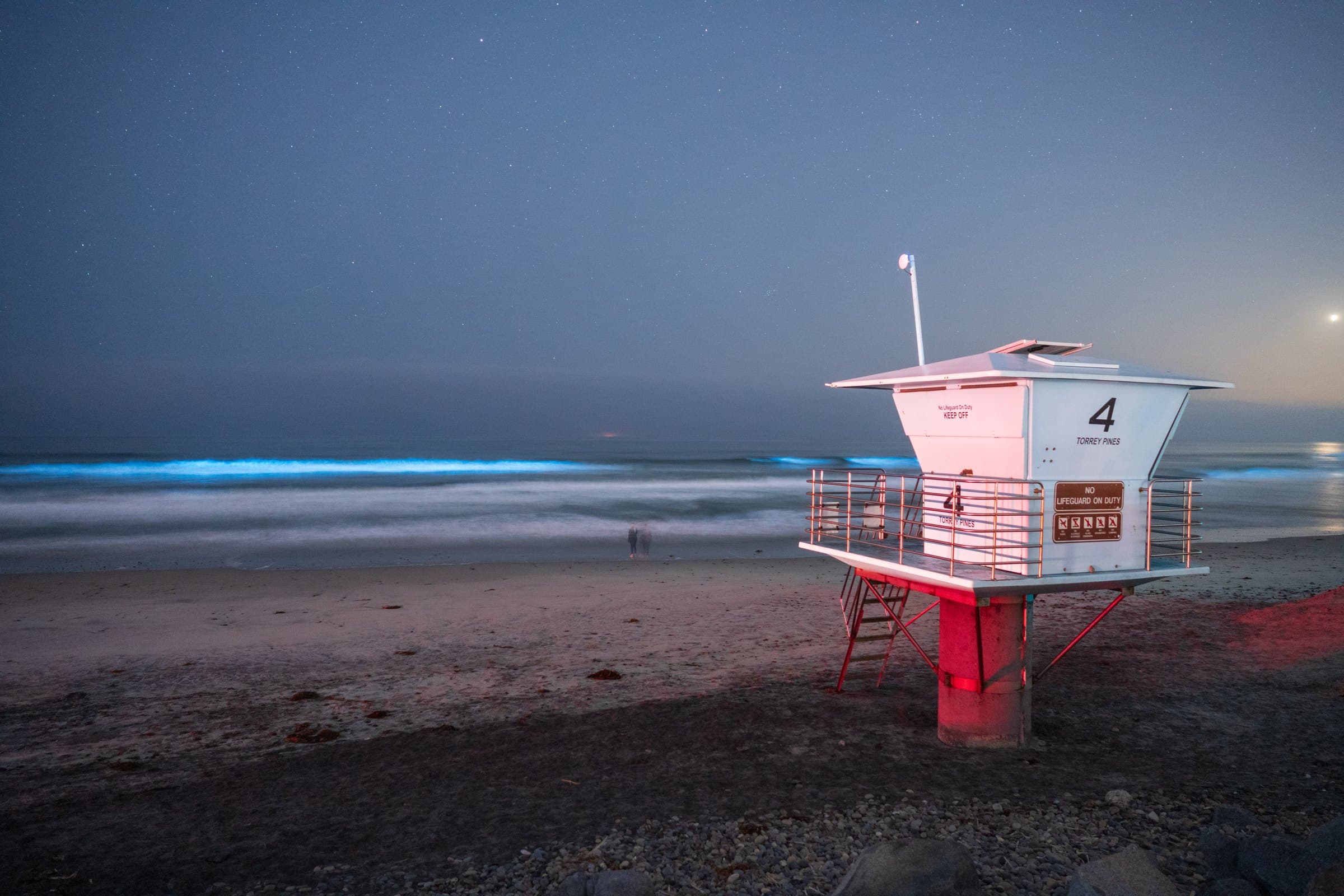 A dark nighttime sea lit by a soft, uniform glow rising from the water