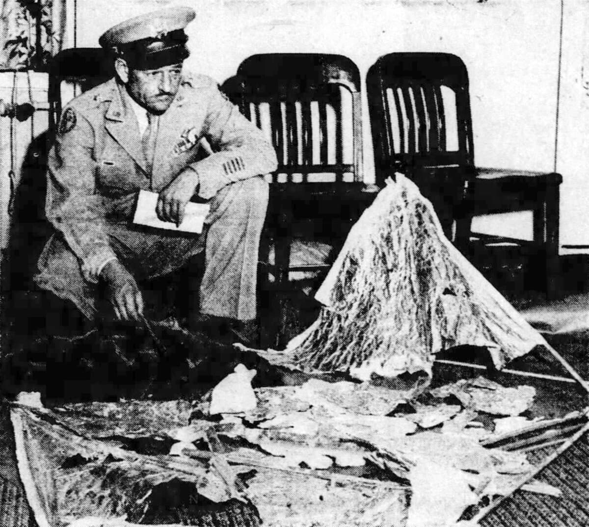 General Roger Ramey crouching with debris from the Roswell crash in his office at Fort Worth