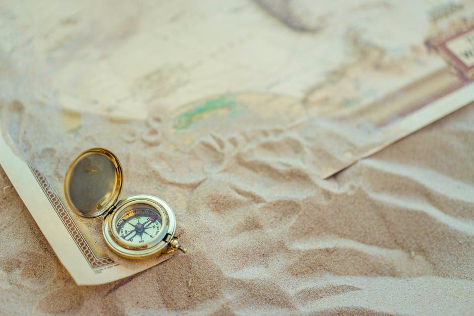 A vintage compass resting on sand beside an old map, symbolizing the centuries of exploration and treasure hunting that have defined Oak Island's history