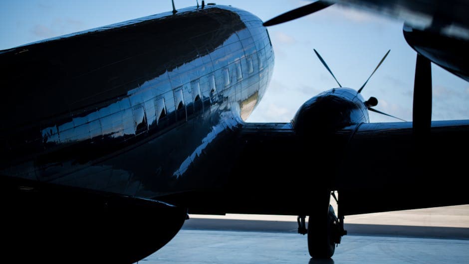 Dramatic silhouette of a vintage aircraft inside a hangar with the sky in the background