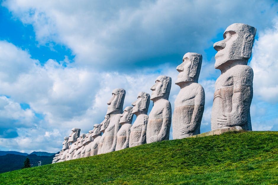 Row of majestic Moai statues on a grassy hill with cloudy blue sky on Easter Island
