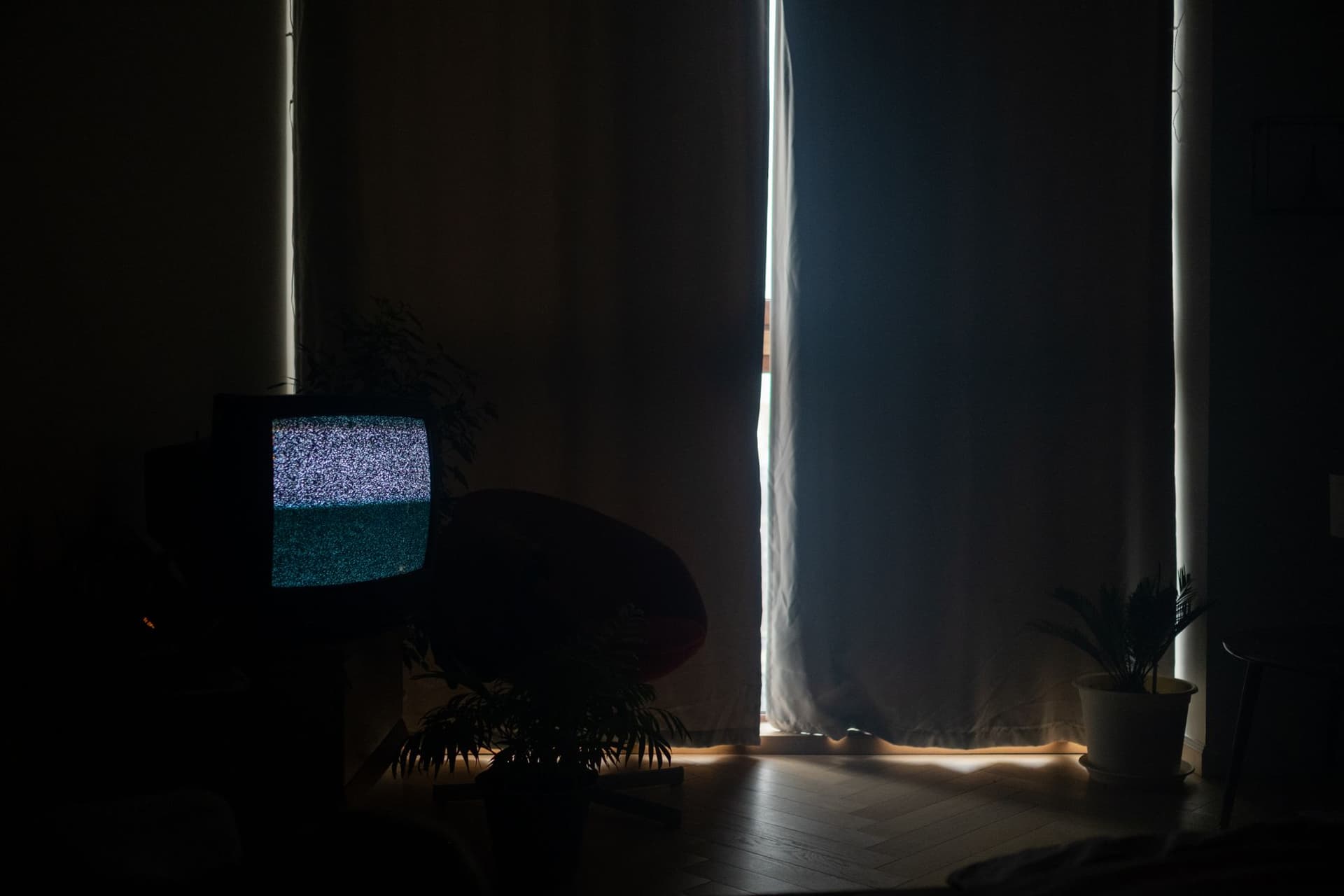 A dimly lit living room with an old television glowing with static in the dark