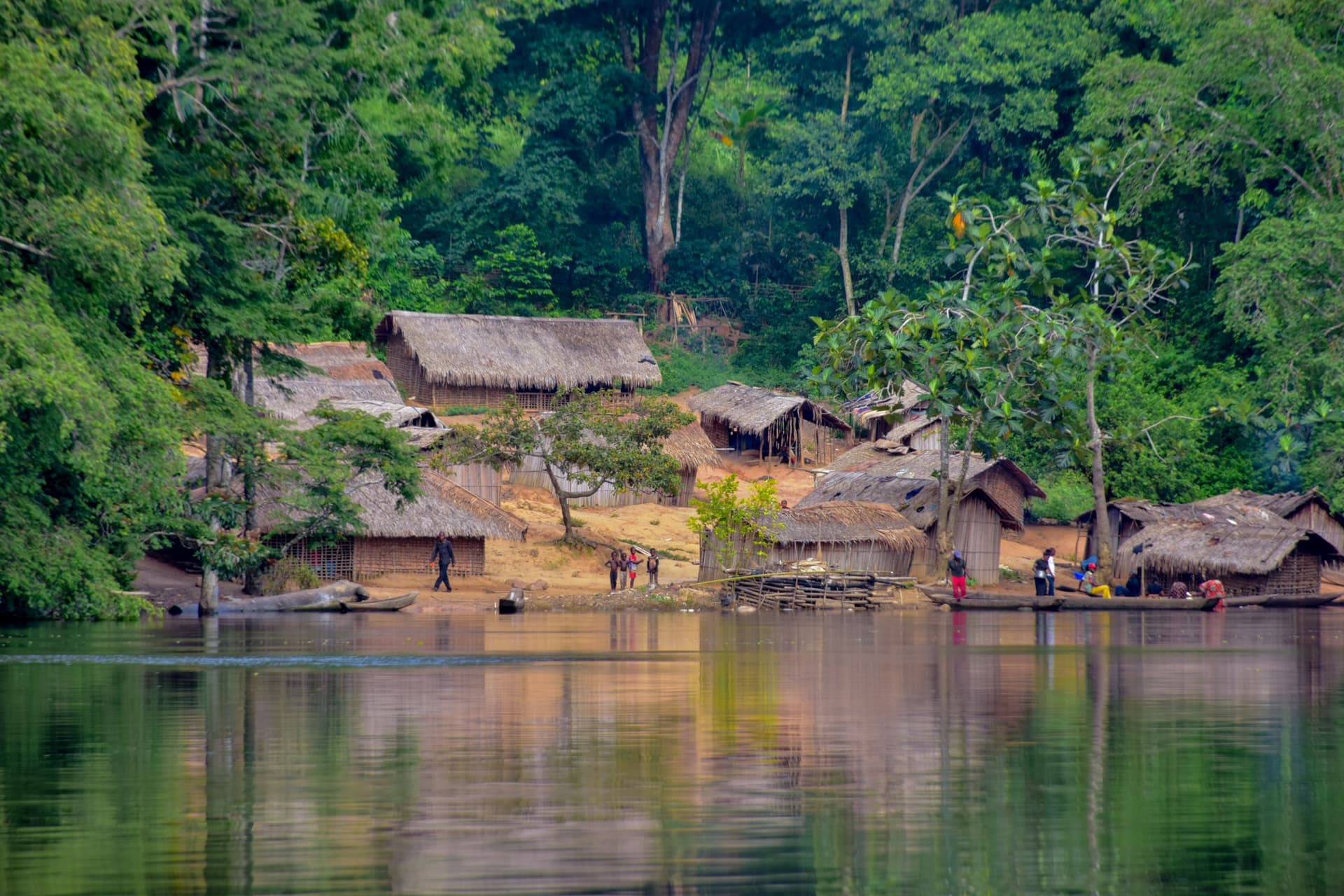 Mist hanging over a wide Congo River channel lined with dense rainforest at dawn