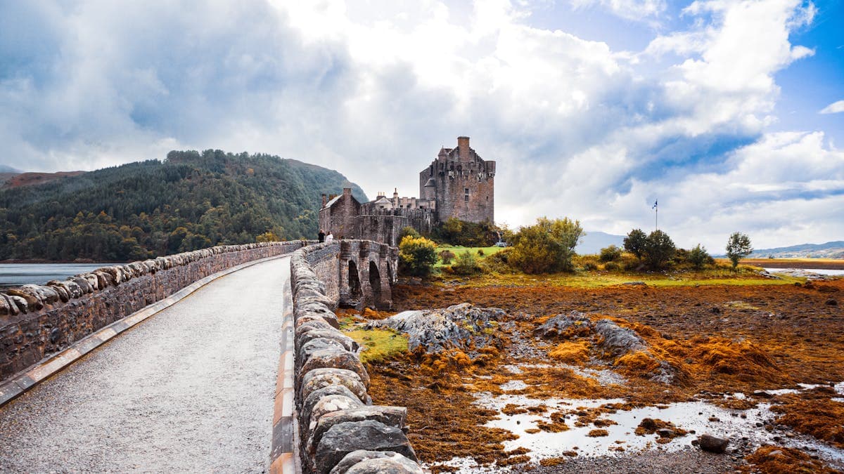 Scenic view of a stone bridge and castle in the misty Scottish Highlands
