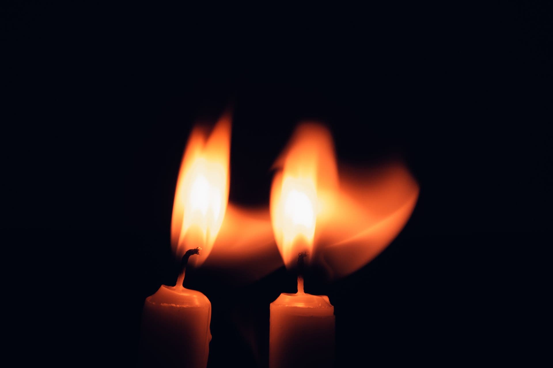 A single candle flame burning brightly against surrounding darkness