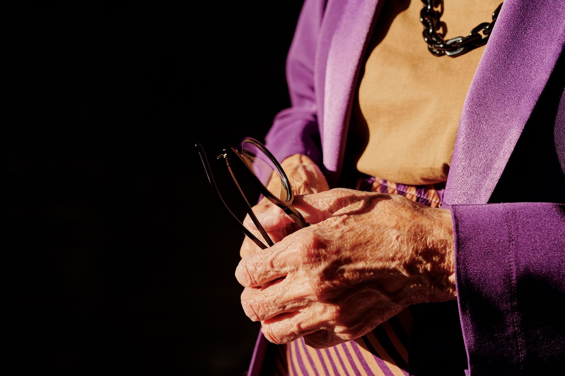 An elderly person's hands resting in soft light