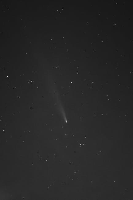 A bright comet with a glowing tail streaks across a star-filled night sky